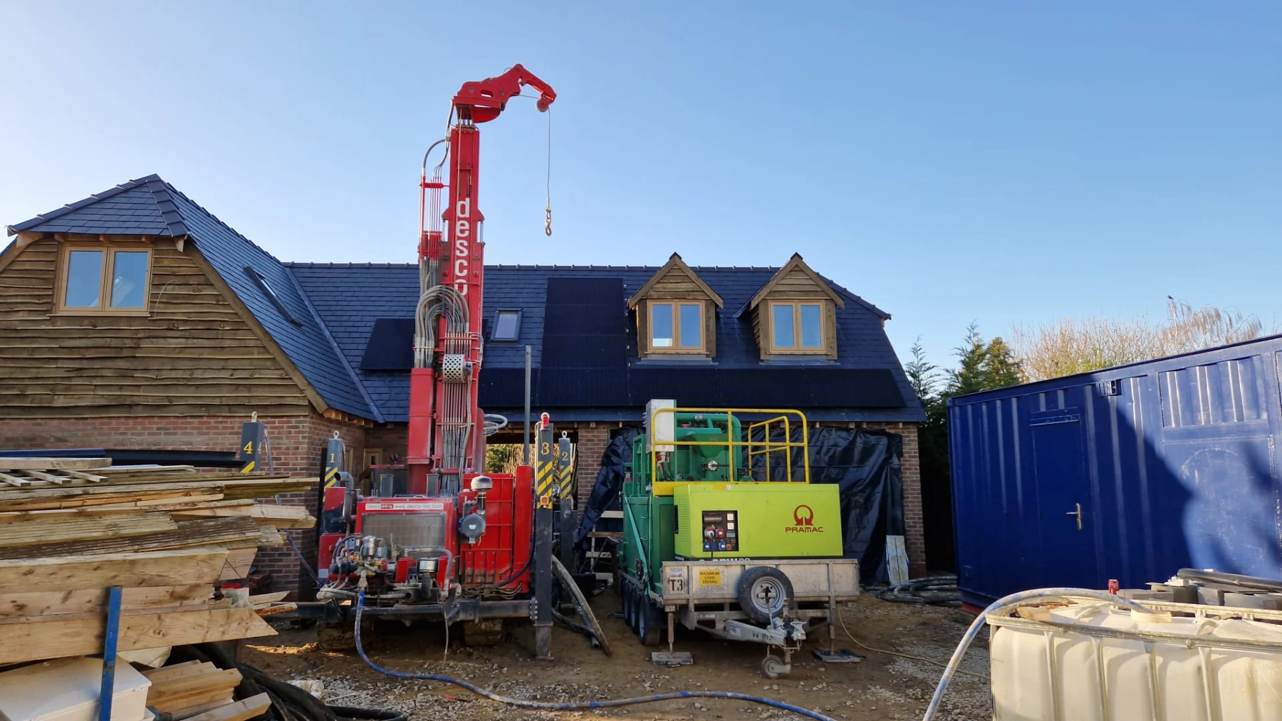 Thermal Earth borehole drilling rig working beside a home